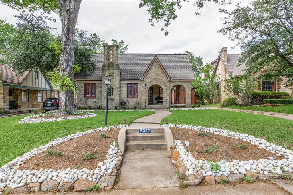 a white house with a big yard plants and large trees