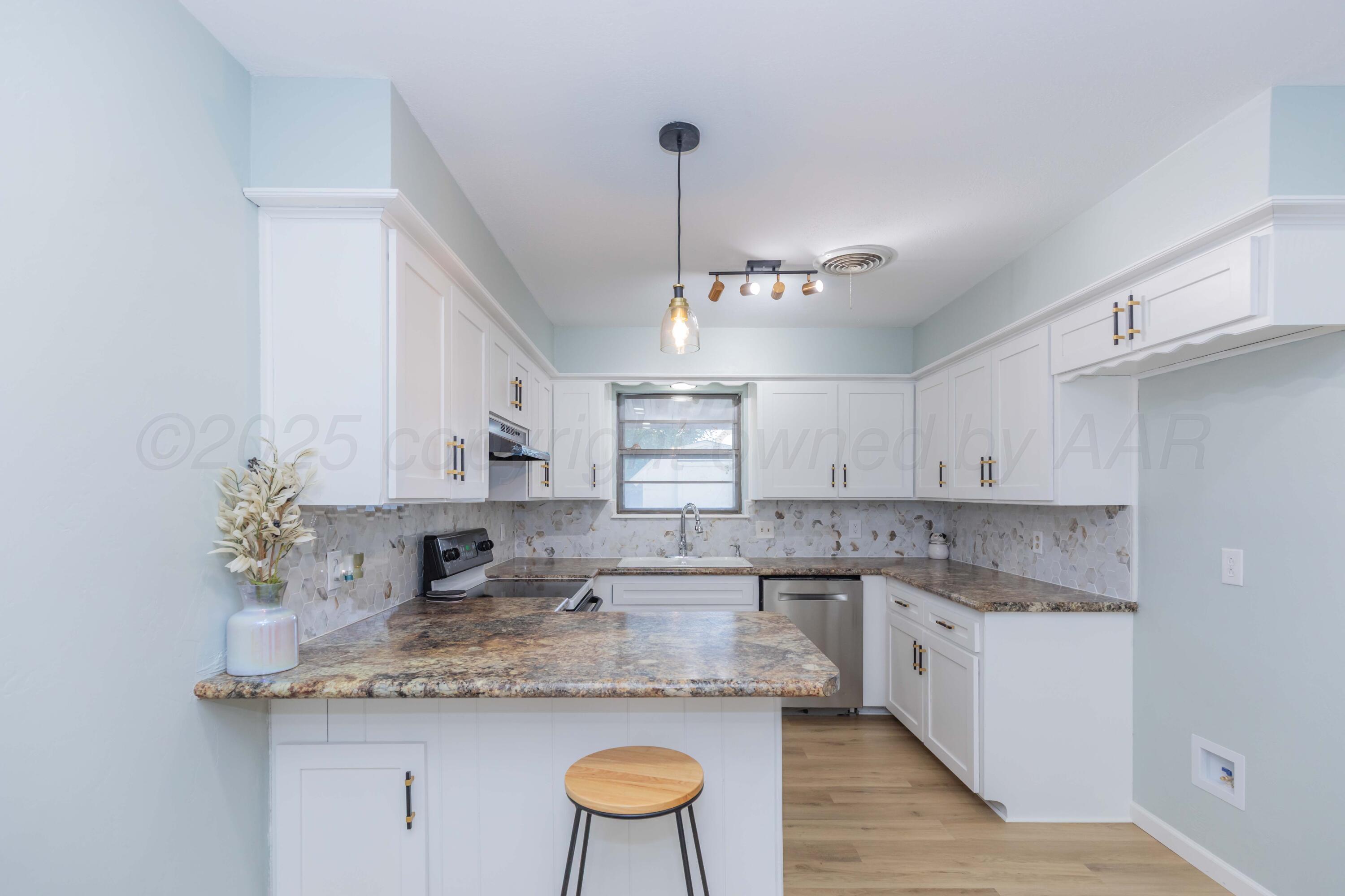 7912 Gerald Drive Amarillo, TX 79121 - Photo 11 of 45 a kitchen with stainless steel appliances granite countertop a sink a stove a refrigerator and island with wooden floor
