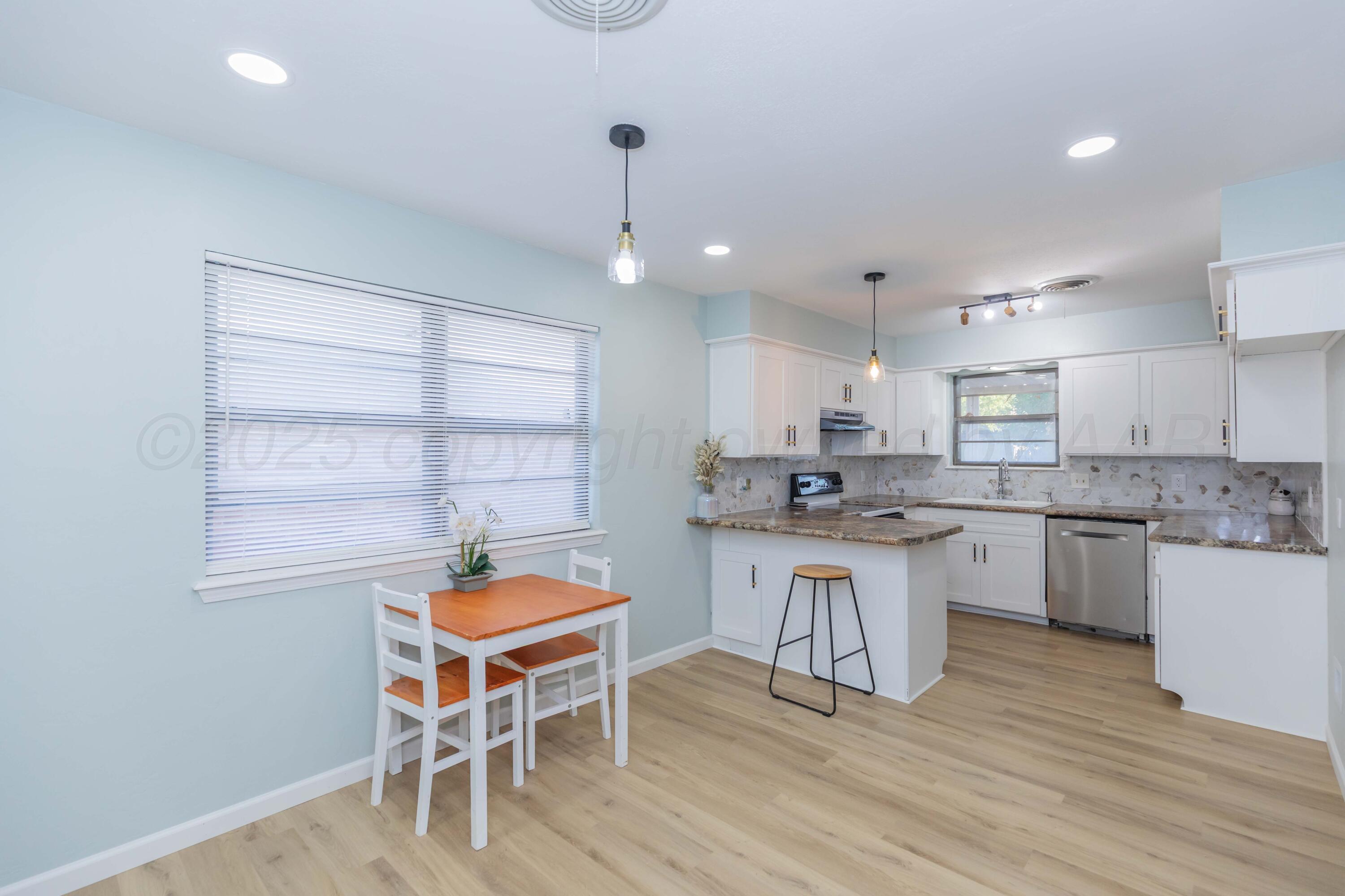 7912 Gerald Drive Amarillo, TX 79121 - Photo 18 of 45 a kitchen with stainless steel appliances granite countertop a white cabinets and wooden floor