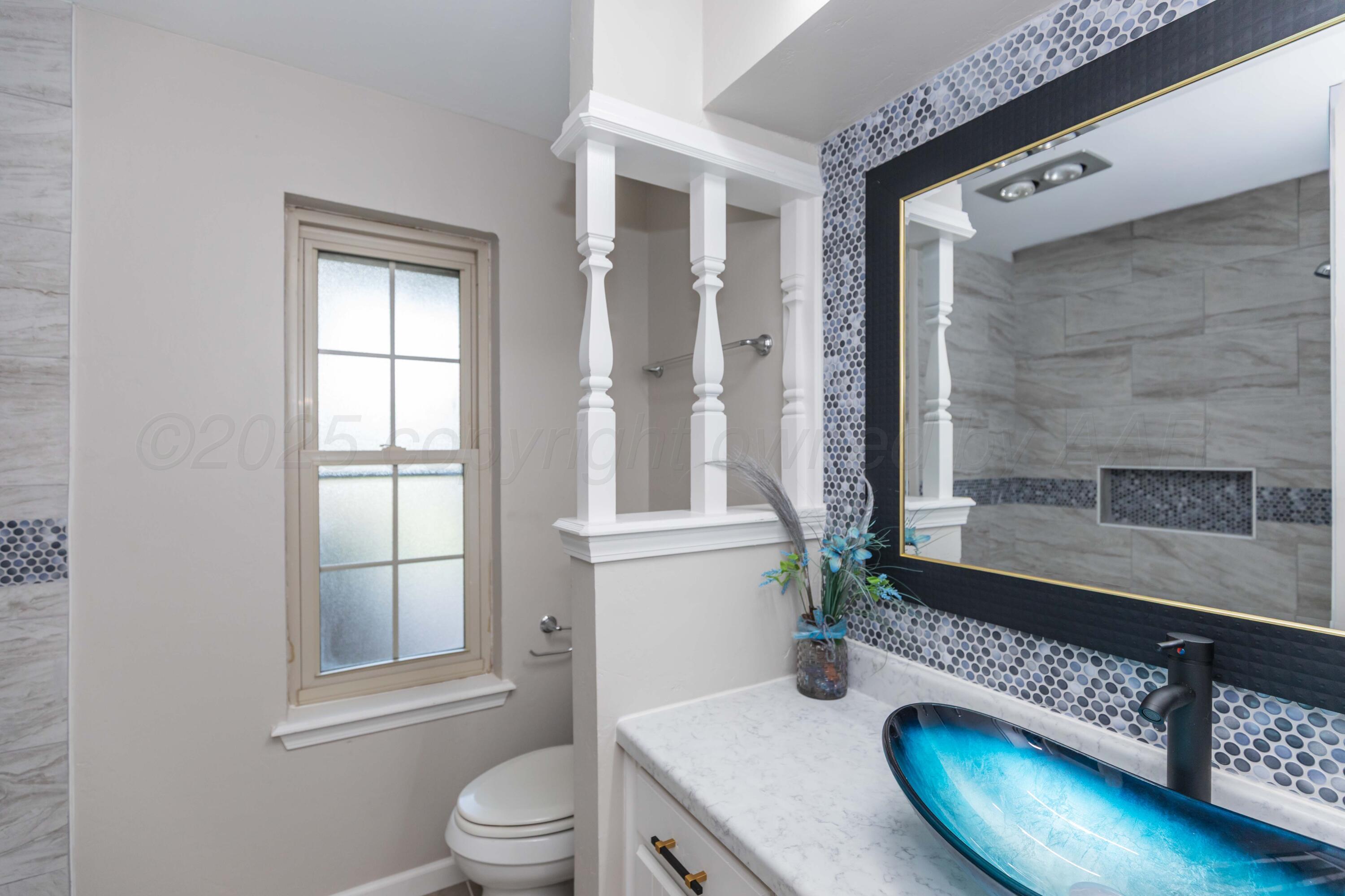 7912 Gerald Drive Amarillo, TX 79121 - Photo 32 of 45 a bathroom with a granite countertop sink toilet a mirror and shower