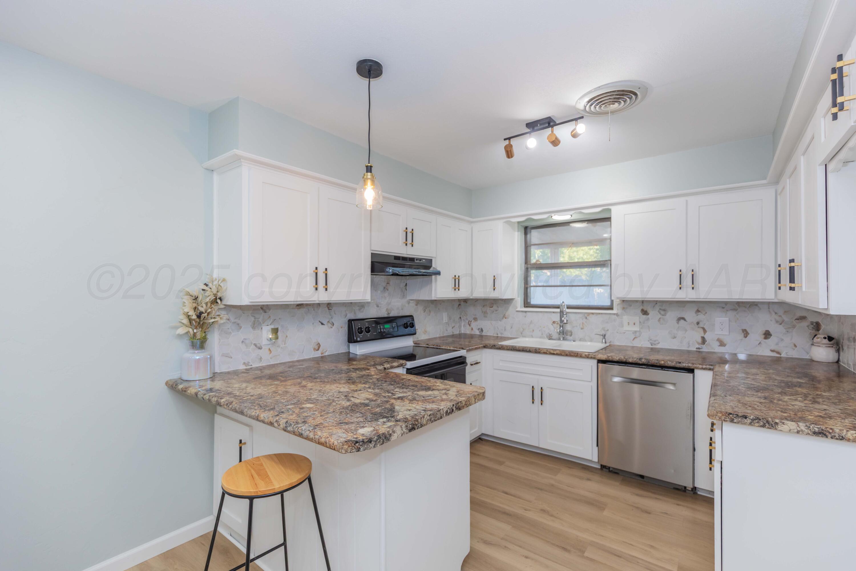 7912 Gerald Drive Amarillo, TX 79121 - Photo 10 of 45 a kitchen with stainless steel appliances granite countertop a sink a stove a refrigerator and island with wooden floor