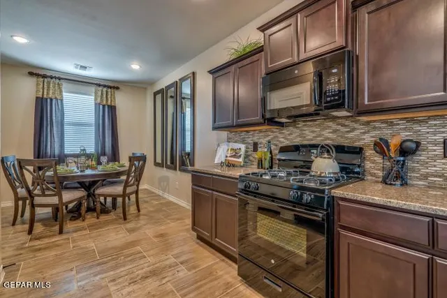 a kitchen with stainless steel appliances granite countertop a stove top oven a sink dishwasher a dining table and chairs with wooden floor