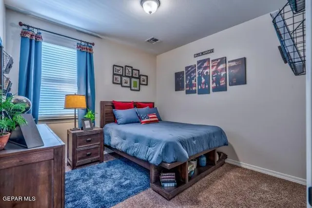 a bedroom with a bed and a potted plant on the dresser