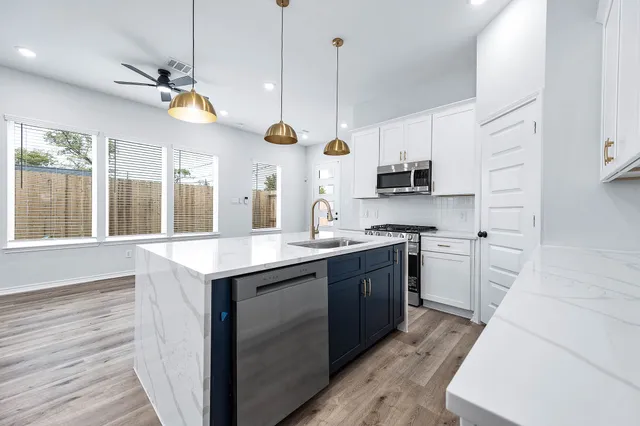 a kitchen with kitchen island granite countertop a sink a counter space appliances and cabinets