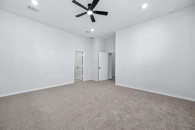 an empty room with a ceiling fan and window