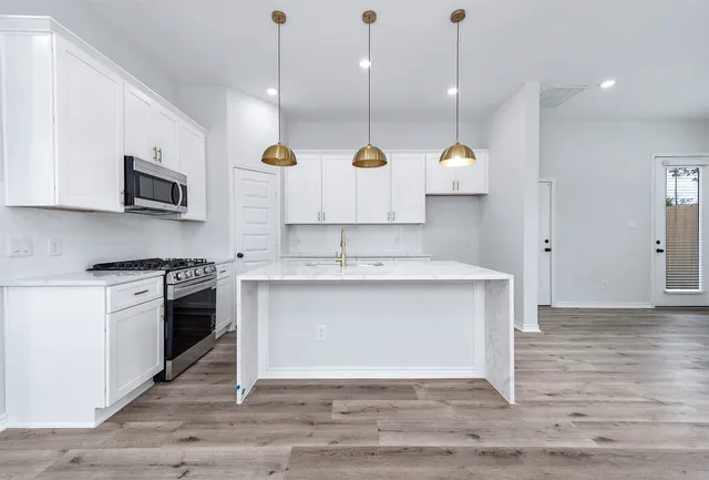 a kitchen with stainless steel appliances granite countertop a sink a stove a microwave a center island and cabinets