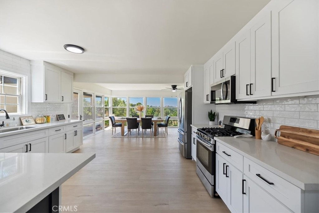 1748 Prince Albert Drive Riverside, CA 92507 - Photo 4 of 42 a kitchen with stainless steel appliances granite countertop a stove top oven a sink a dining table and chairs with white cabinets
