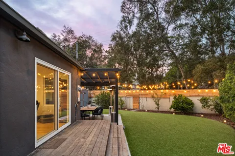 a porch with a table and chairs next to a yard
