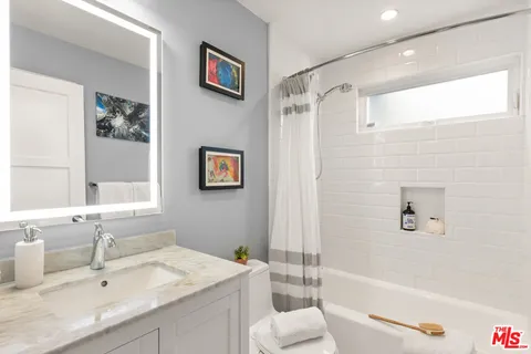 a bathroom with a granite countertop sink a toilet a shower and a mirror