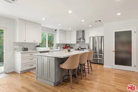 a kitchen with stainless steel appliances granite countertop a table chairs sink refrigerator and cabinets