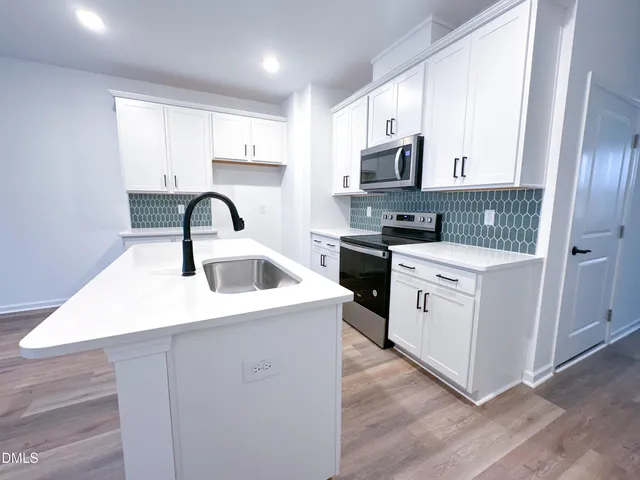 a kitchen with stainless steel appliances a sink a stove a microwave a sink a refrigerator and cabinets