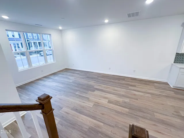 a view of an empty room with window and wooden floor