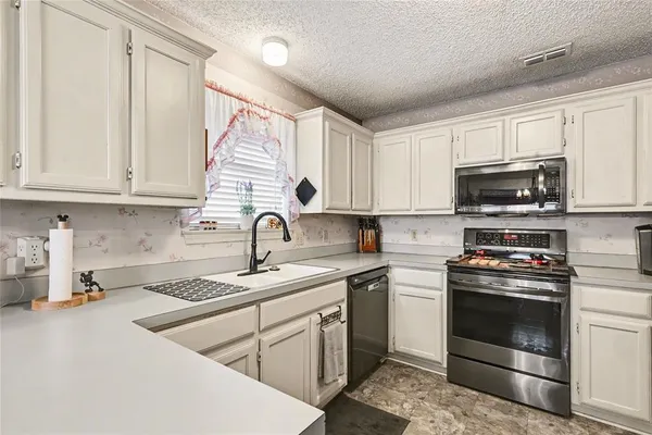 a kitchen with granite countertop white cabinets stainless steel appliances and a sink