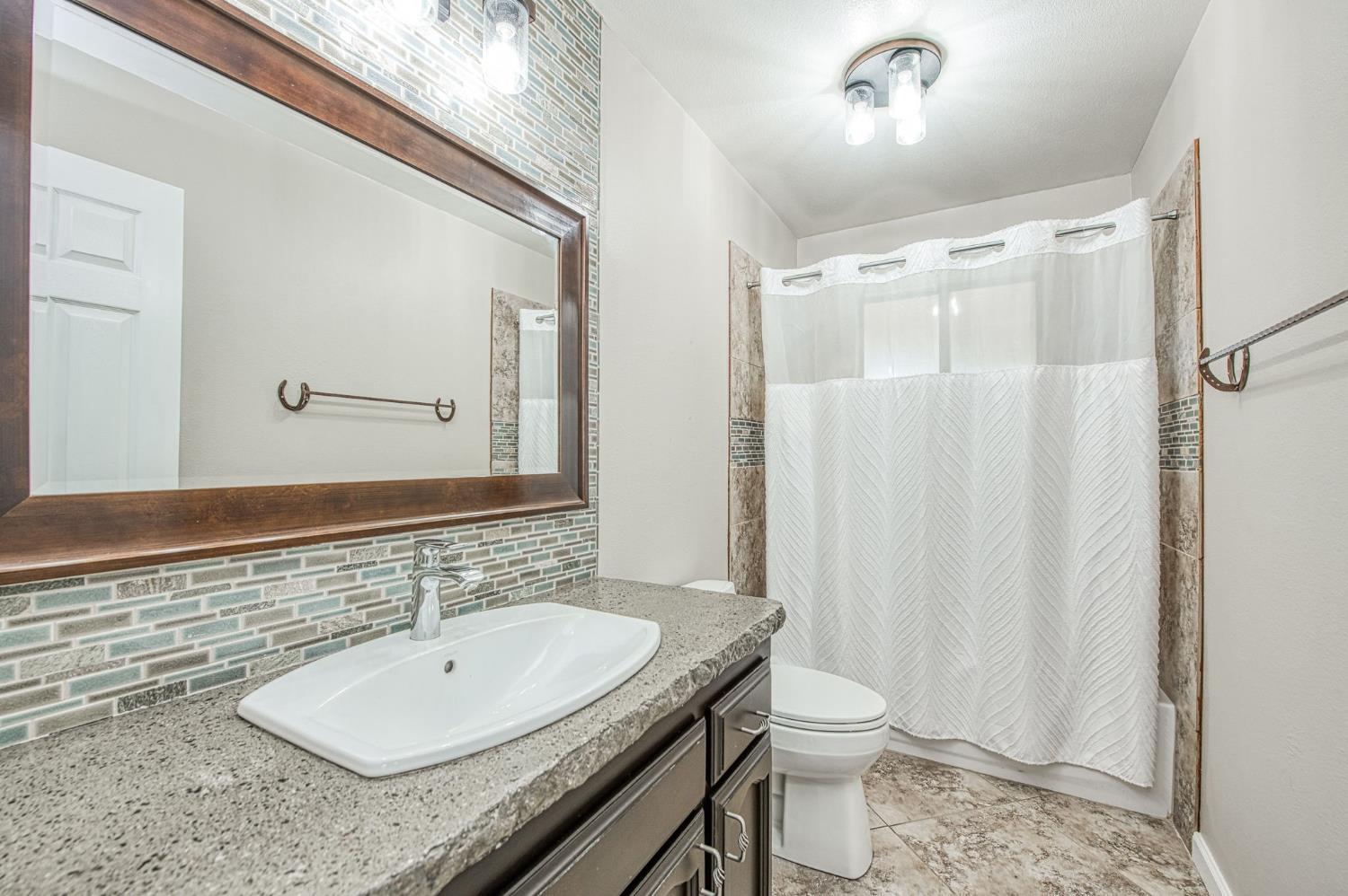 33717 River Knolls Road Coarsegold, CA 93614 - Photo 15 of 66 a bathroom with a granite countertop sink toilet and shower