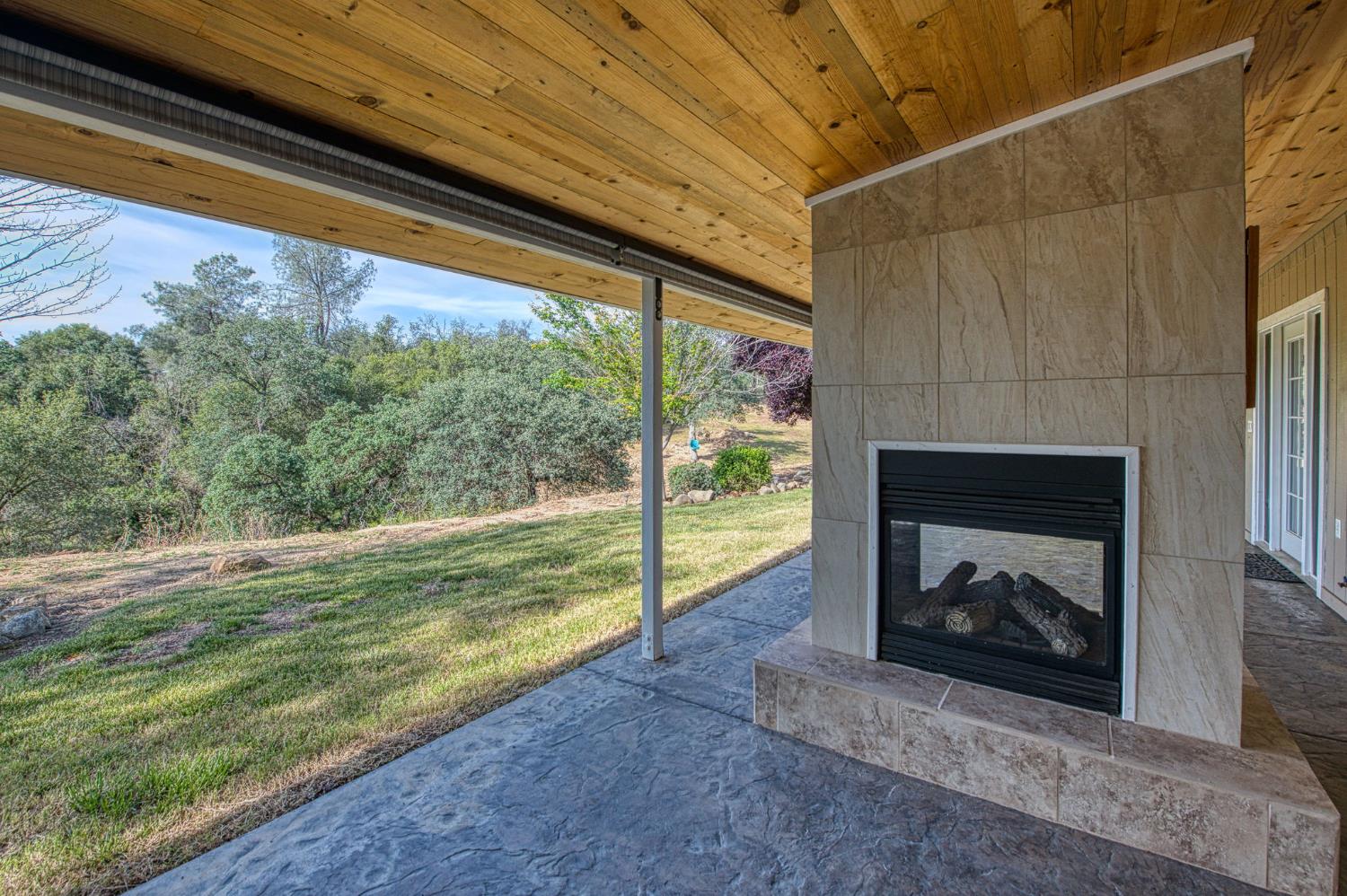 33717 River Knolls Road Coarsegold, CA 93614 - Photo 29 of 66 a living room with a fireplace and a floor to ceiling window
