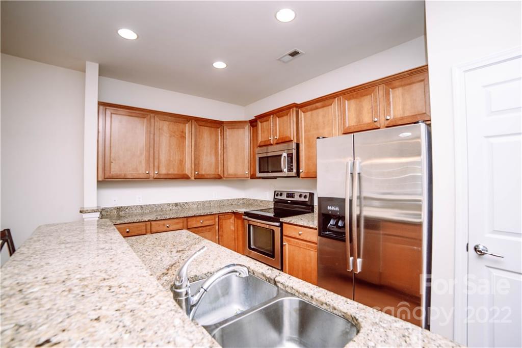 9005 Smokey Hill Road Indian Land, SC 29707 - Photo 3 of 30 a kitchen with stainless steel appliances granite countertop a refrigerator a stove and a sink with wooden floor