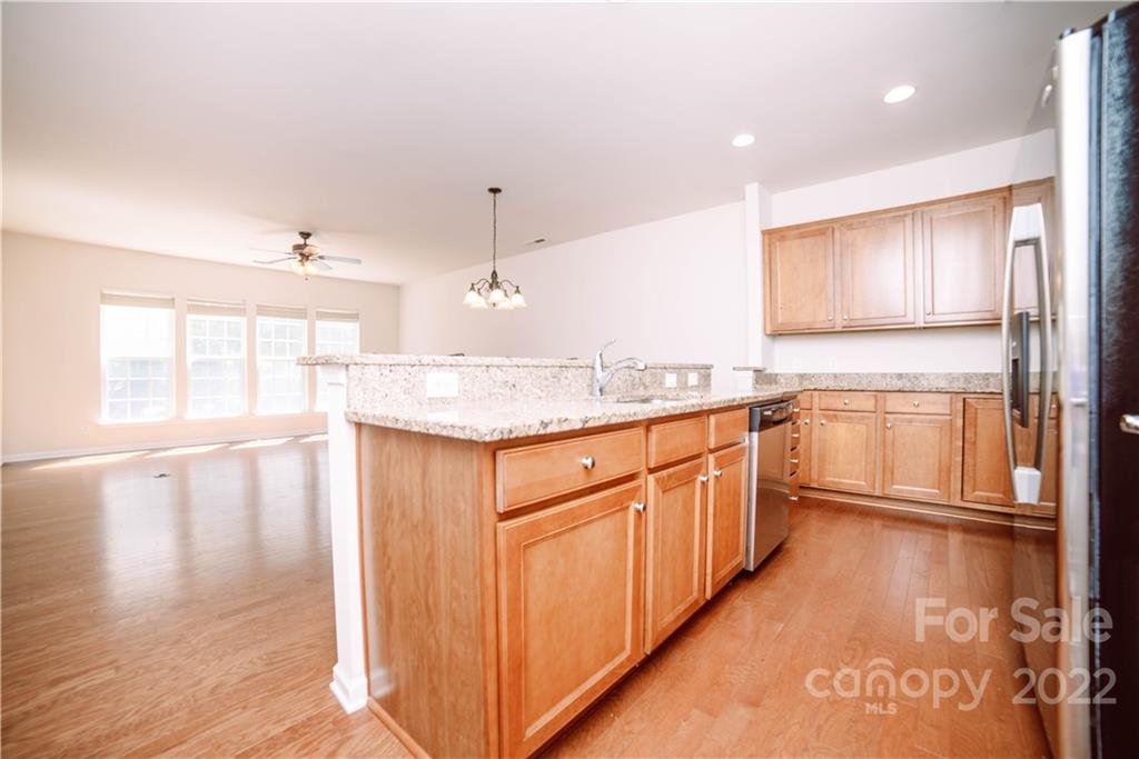 9005 Smokey Hill Road Indian Land, SC 29707 - Photo 7 of 30 a kitchen with stainless steel appliances granite countertop a refrigerator a sink dishwasher and wooden cabinets with wooden floor