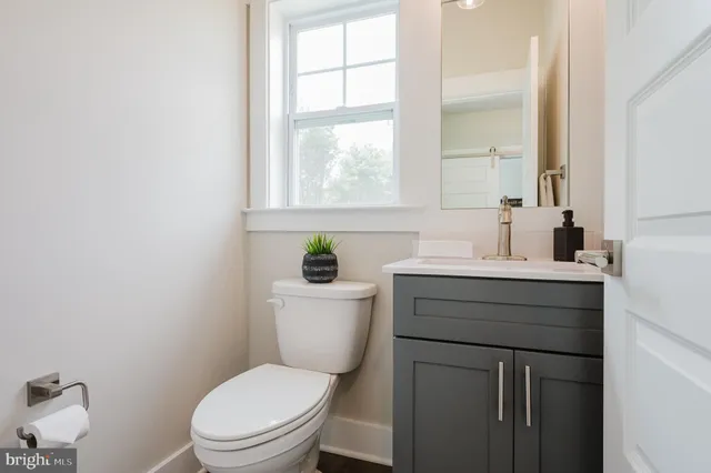 a bathroom with a toilet a sink a vanity a window and mirror