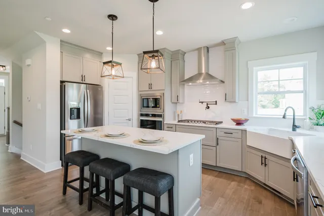 a kitchen with stainless steel appliances granite countertop a sink a stove a refrigerator and island with wooden floor