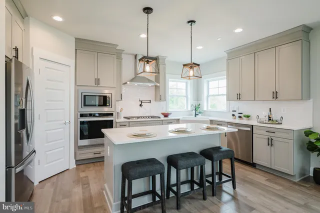 a kitchen with stainless steel appliances granite countertop a sink a stove a refrigerator and island with wooden floor