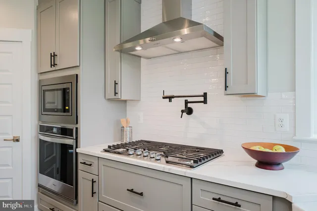 a kitchen with stainless steel appliances a stove and white cabinets