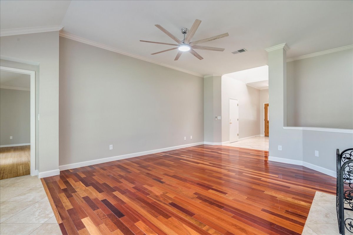 6530 Needham Lane Austin, TX 78739 - Photo 6 of 29 Rich hardwood flooring stretches across this naturally illuminated living space, crowned by a contemporary ceiling fan.