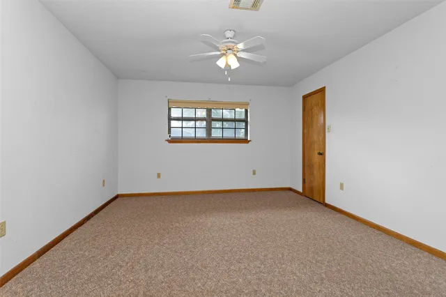 an empty room with windows and ceiling fan