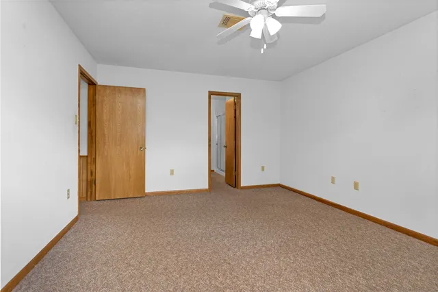 an empty room with a chandelier fan and windows