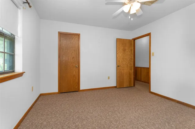an empty room with a chandelier fan and windows