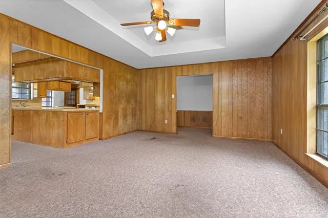 an empty room with chandelier fan and windows