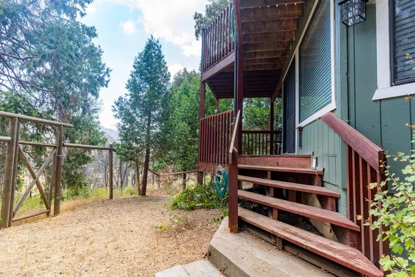 a view of a deck with table and chairs a barbeque with wooden fence and plants