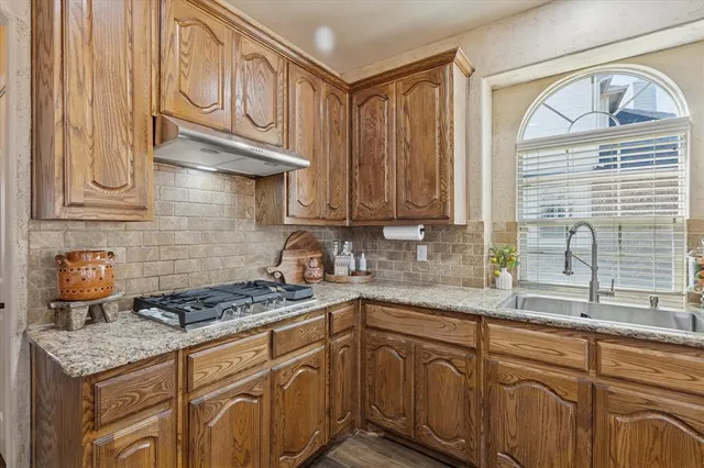a kitchen with stainless steel appliances granite countertop a sink a stove and cabinets