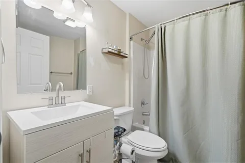 a bathroom with a sink a mirror a toilet and shower curtain