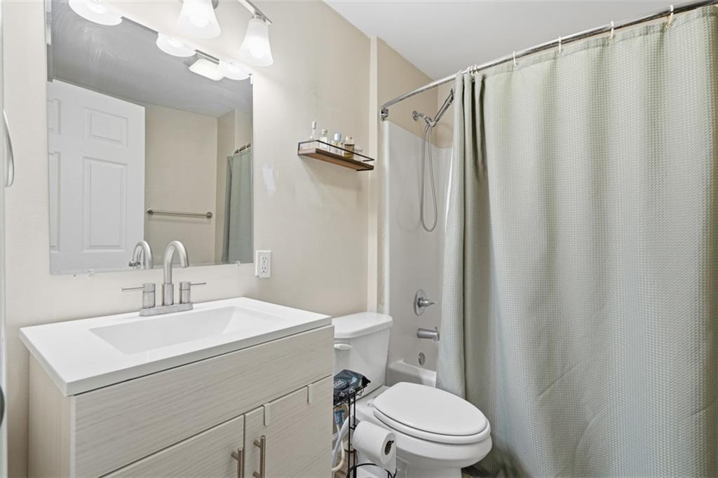1202 Sarah Street Pittsburgh, PA 15203 - Photo 12 of 37 a bathroom with a sink a mirror a toilet and shower curtain