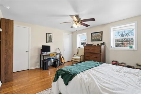 a bedroom with a bed and dresser with wooden floor