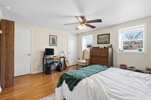 a bedroom with a bed and dresser with wooden floor