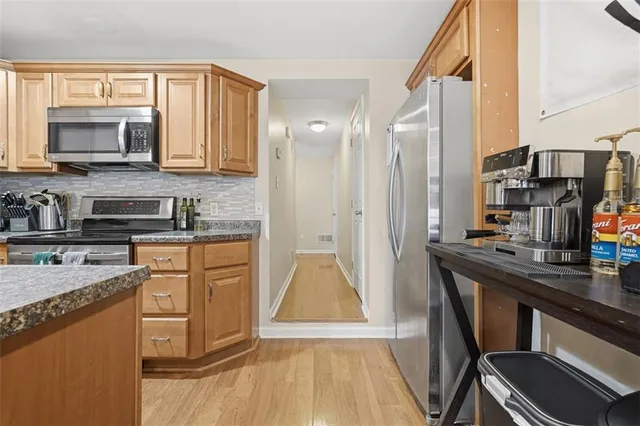 a kitchen with stainless steel appliances granite countertop a refrigerator a stove and a sink with wooden floor