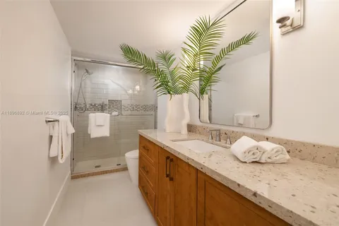 a bathroom with a granite countertop sink a mirror and a shower