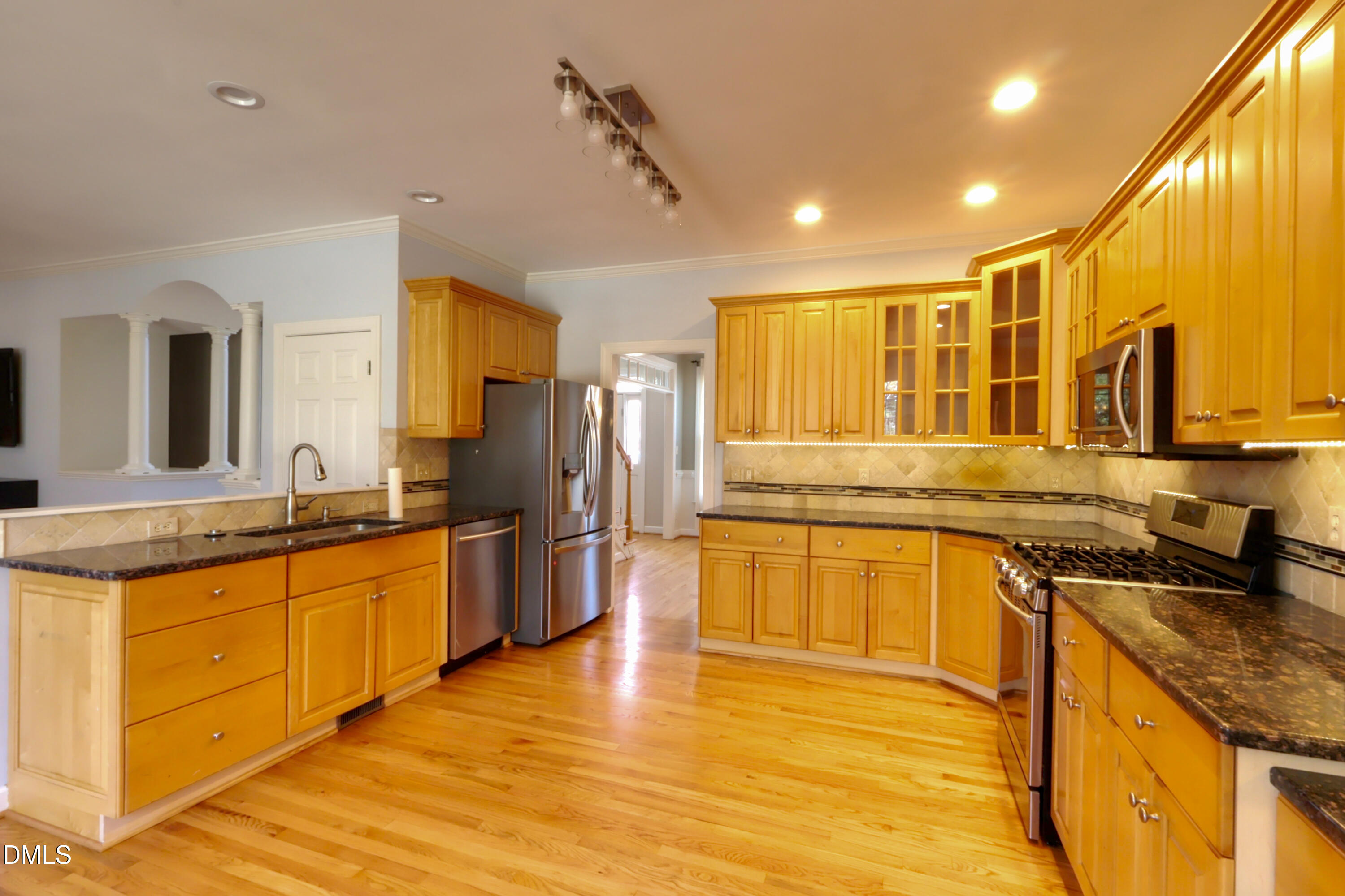 2504 Pennyshire Lane Raleigh, NC 27606 - Photo 11 of 32 a large kitchen with stainless steel appliances granite countertop a sink and a stove top oven with wooden floor