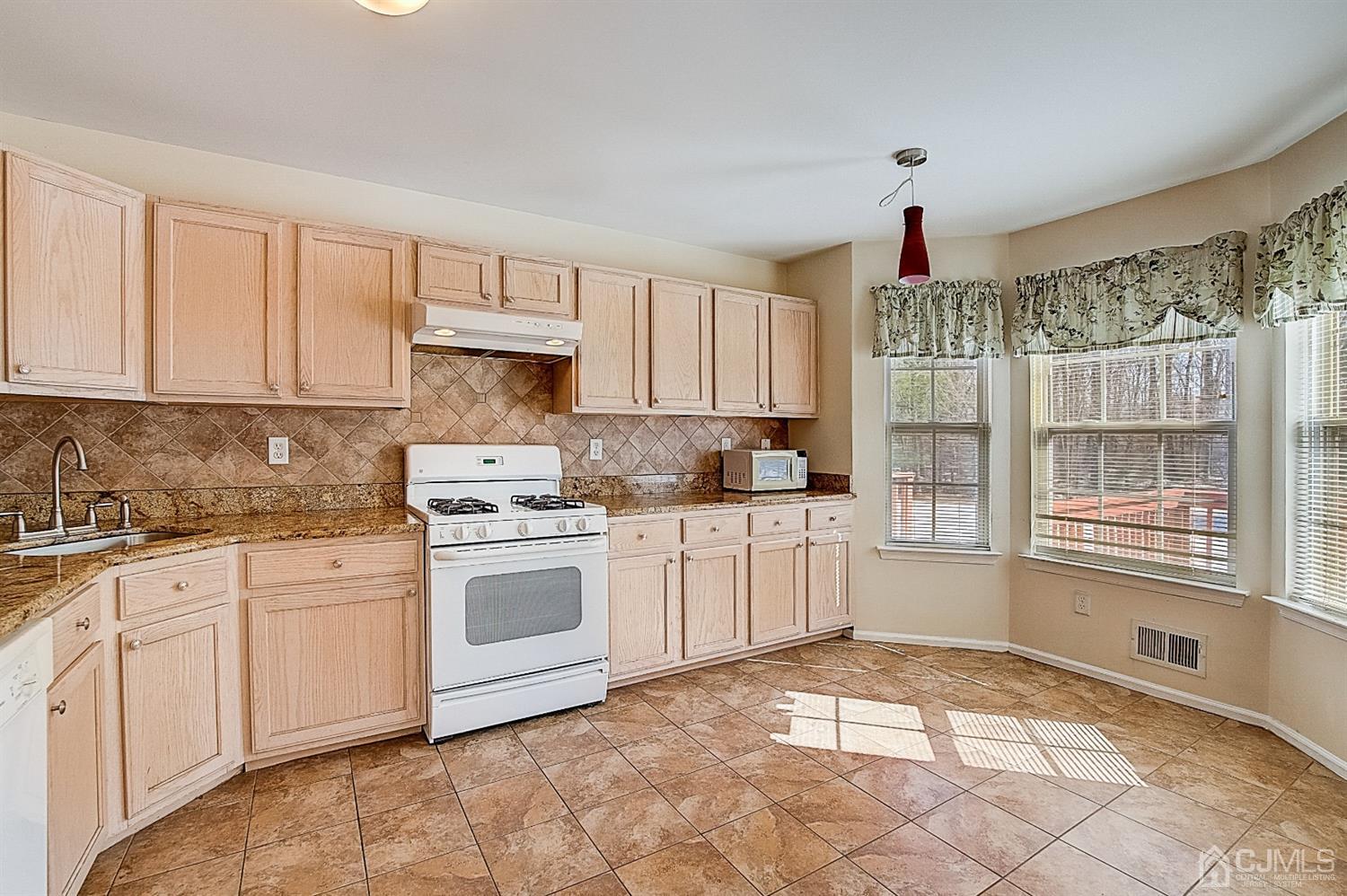 38 Hawthorne Road North Brunswick, NJ 08902 - Photo 8 of 26 a kitchen with granite countertop a stove a sink and white cabinets
