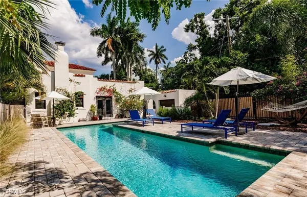 a view of a swimming pool with lawn chairs under an umbrella