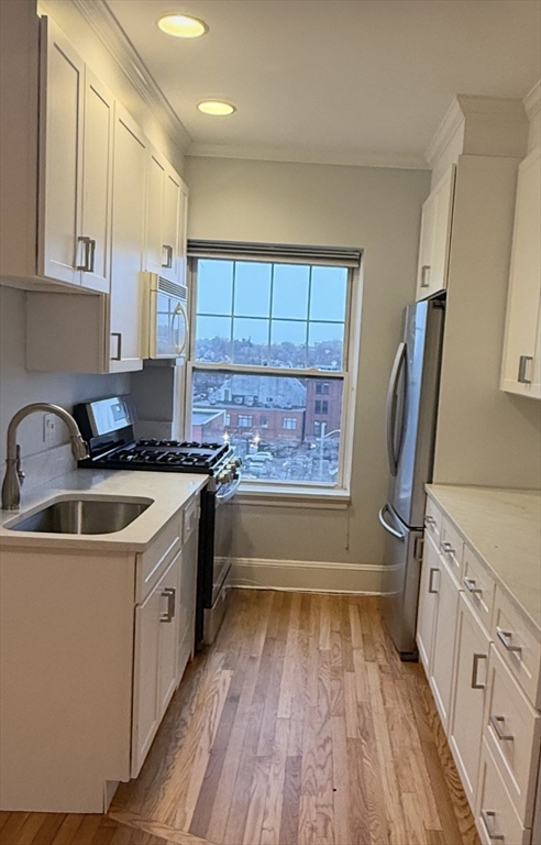 21 Bradlee Road, Unit 52 Medford, MA 02155 - Photo 7 of 22 a kitchen with wooden floors sink and cabinets