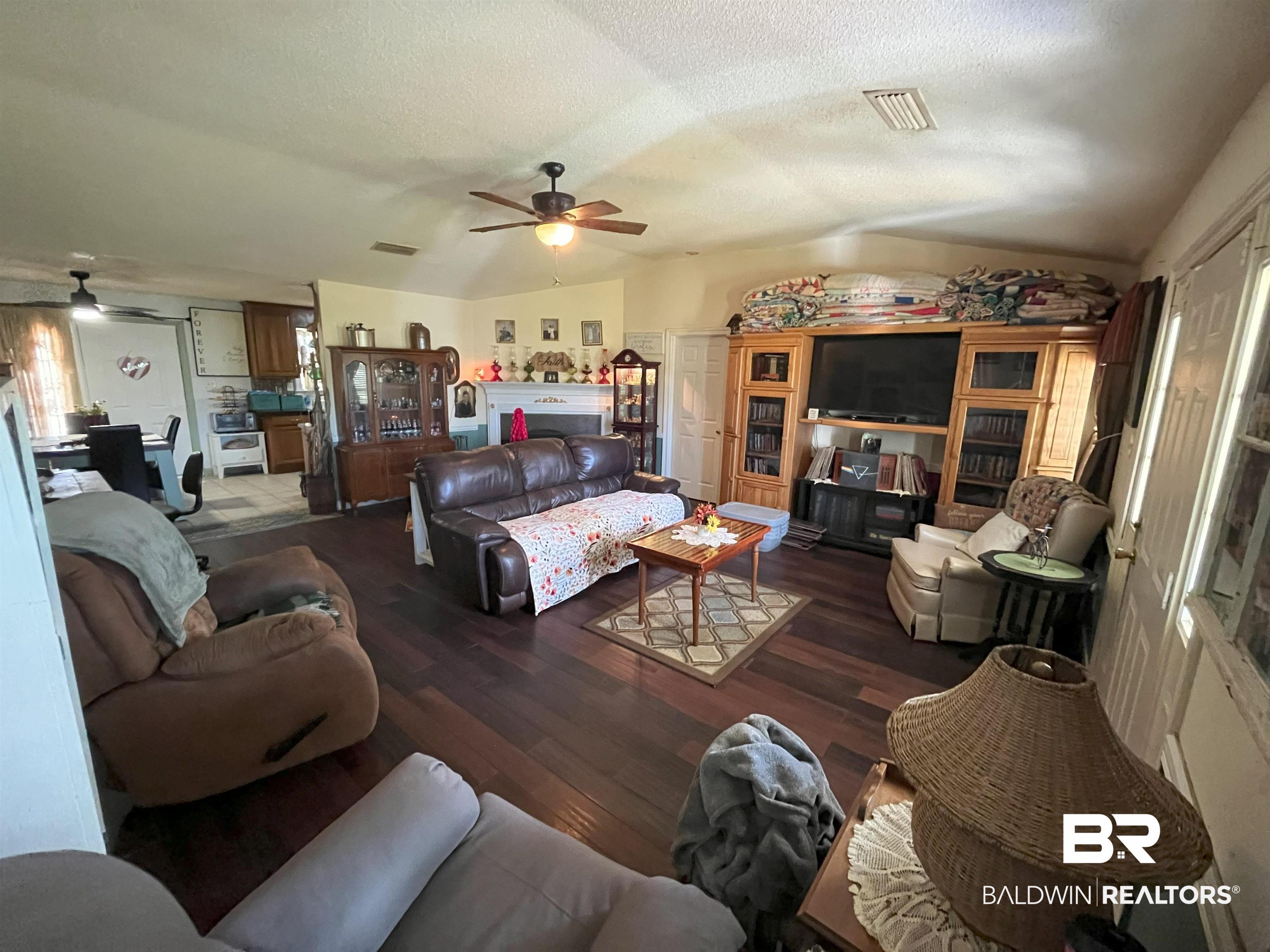 7851 Highway 98 Fairhope, AL 36532 - Photo 8 of 40 Living room featuring vaulted ceiling, wood finished floors, a textured ceiling, and ceiling fan