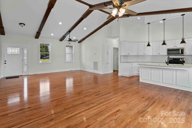 a view of a kitchen with kitchen island a sink wooden floor and stainless steel appliances