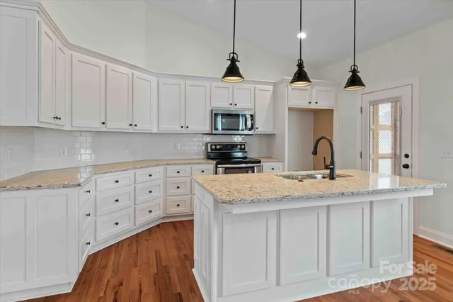 a kitchen with granite countertop a sink cabinets and stainless steel appliances