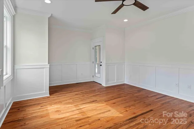 an empty room with wooden floor cabinet and windows