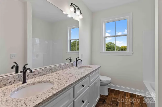 a bathroom with a granite countertop sink a toilet and mirror