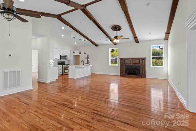 a view of empty room with a fireplace and wooden floor