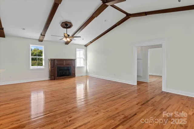 a view of empty room with wooden floor and a window