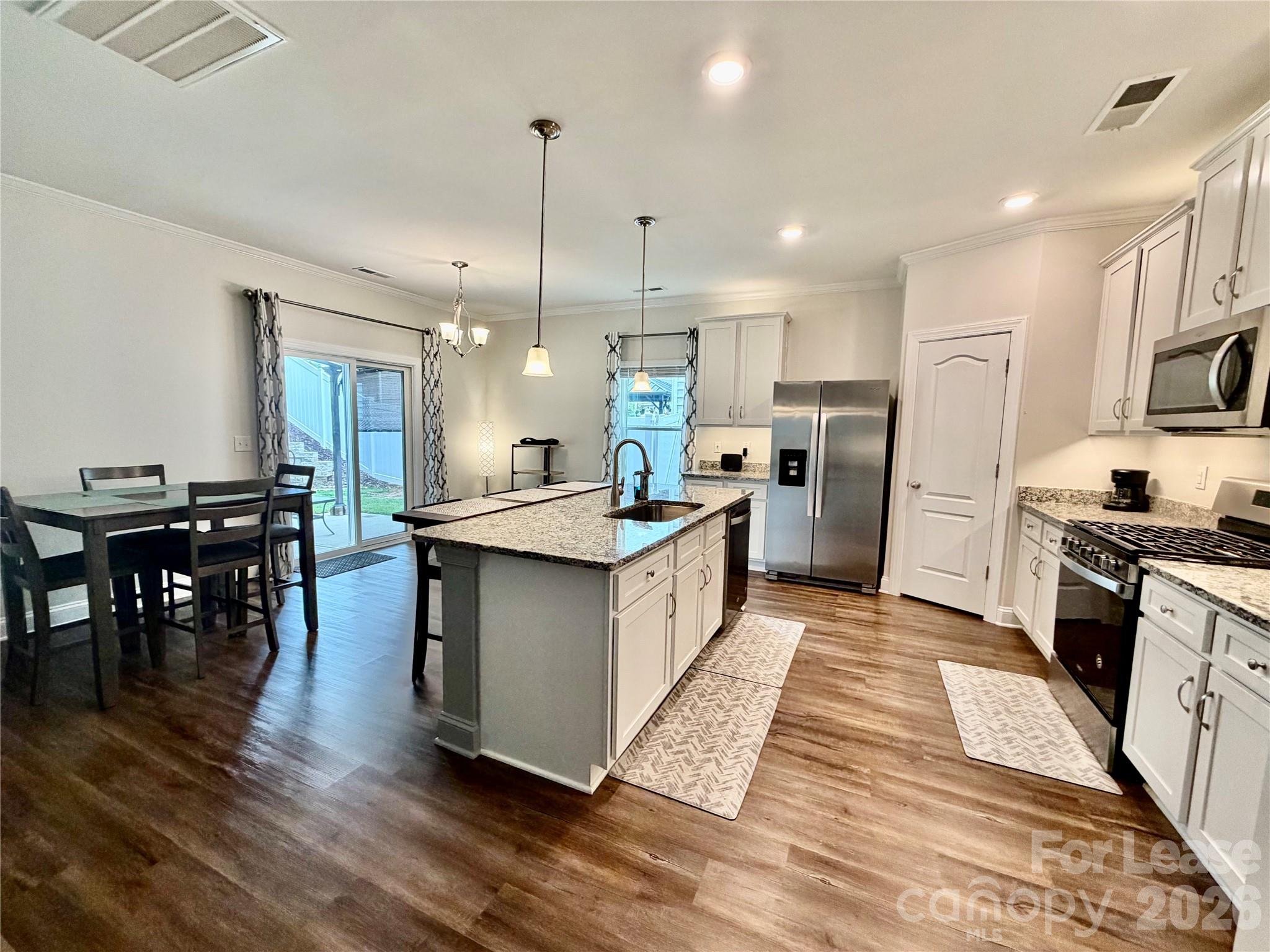 1220 Pecan Ridge Road Fort Mill, SC 29715 - Photo 4 of 25 a large kitchen with stainless steel appliances kitchen island granite countertop a large island a stove a refrigerator a sink a dining table and chairs with wooden floor
